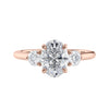 Oval diamond 3 stone engagement ring with small side diamonds rose gold front view.
