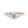 Round brilliant cut diamond 3 stone engagement ring with small side diamonds rose gold front view.