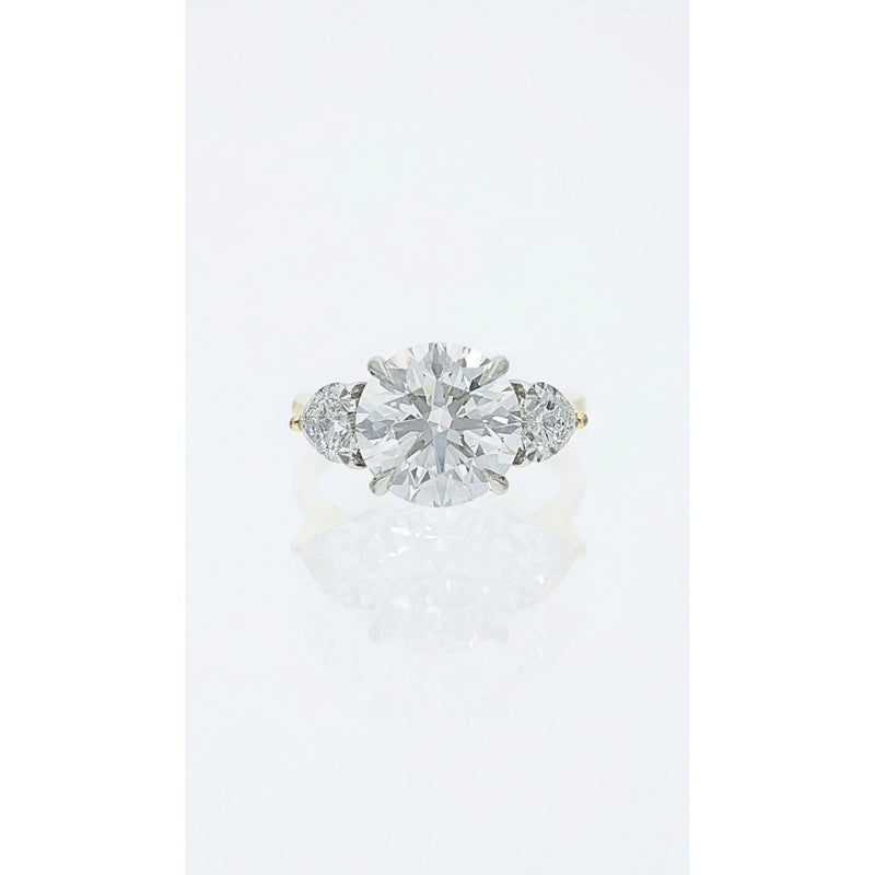 three stone diamond ring with round centre and heart shaped side diamonds in gold and platinum