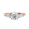 Rose gold round and pear three stone natural diamond engagement ring front view.